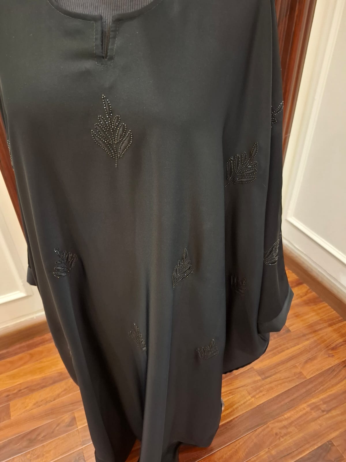 Dark gray sweatshirt with embroidered designs on a wooden floor.