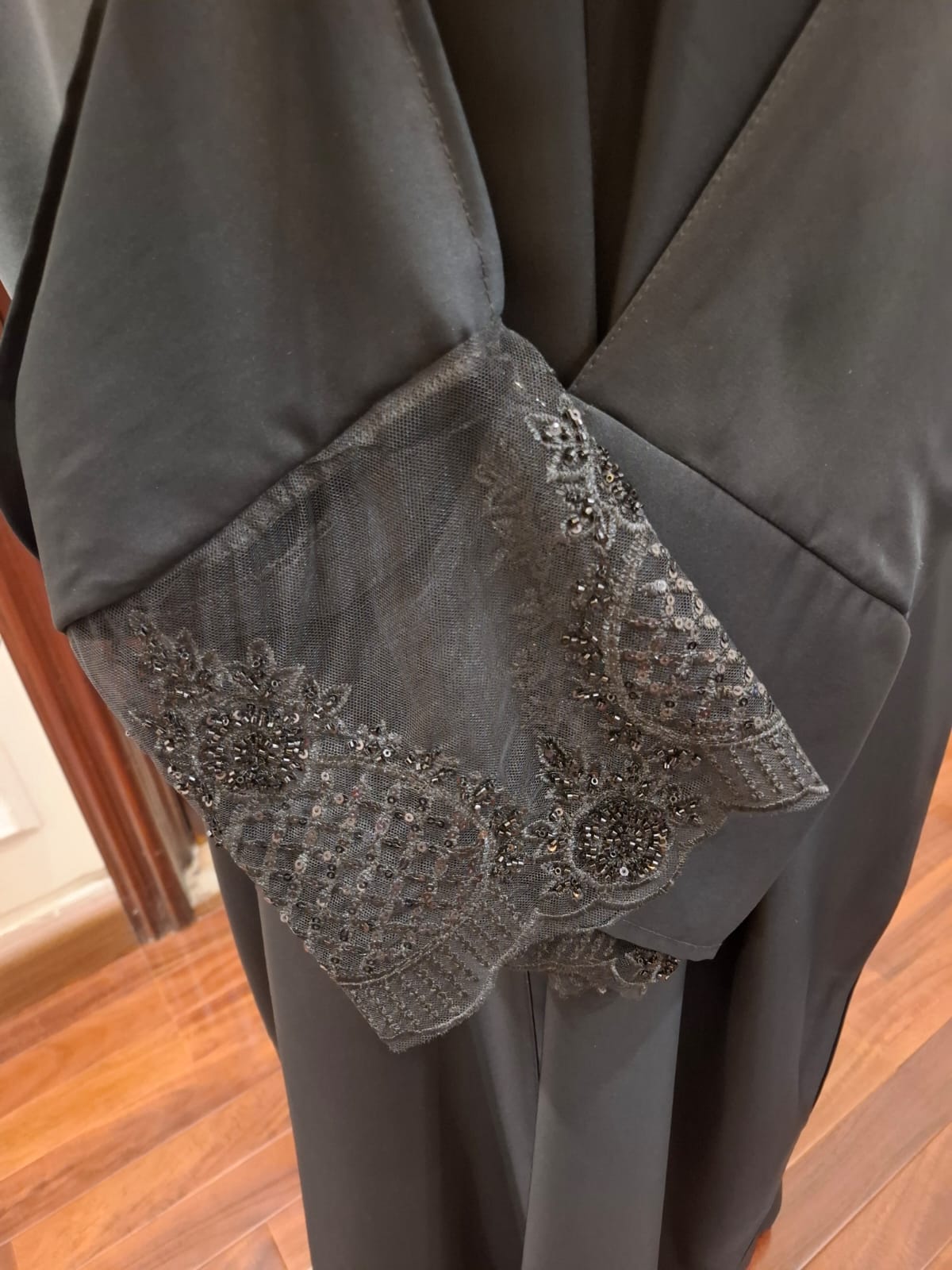 Dark gray pants with lace detailing on a wooden floor