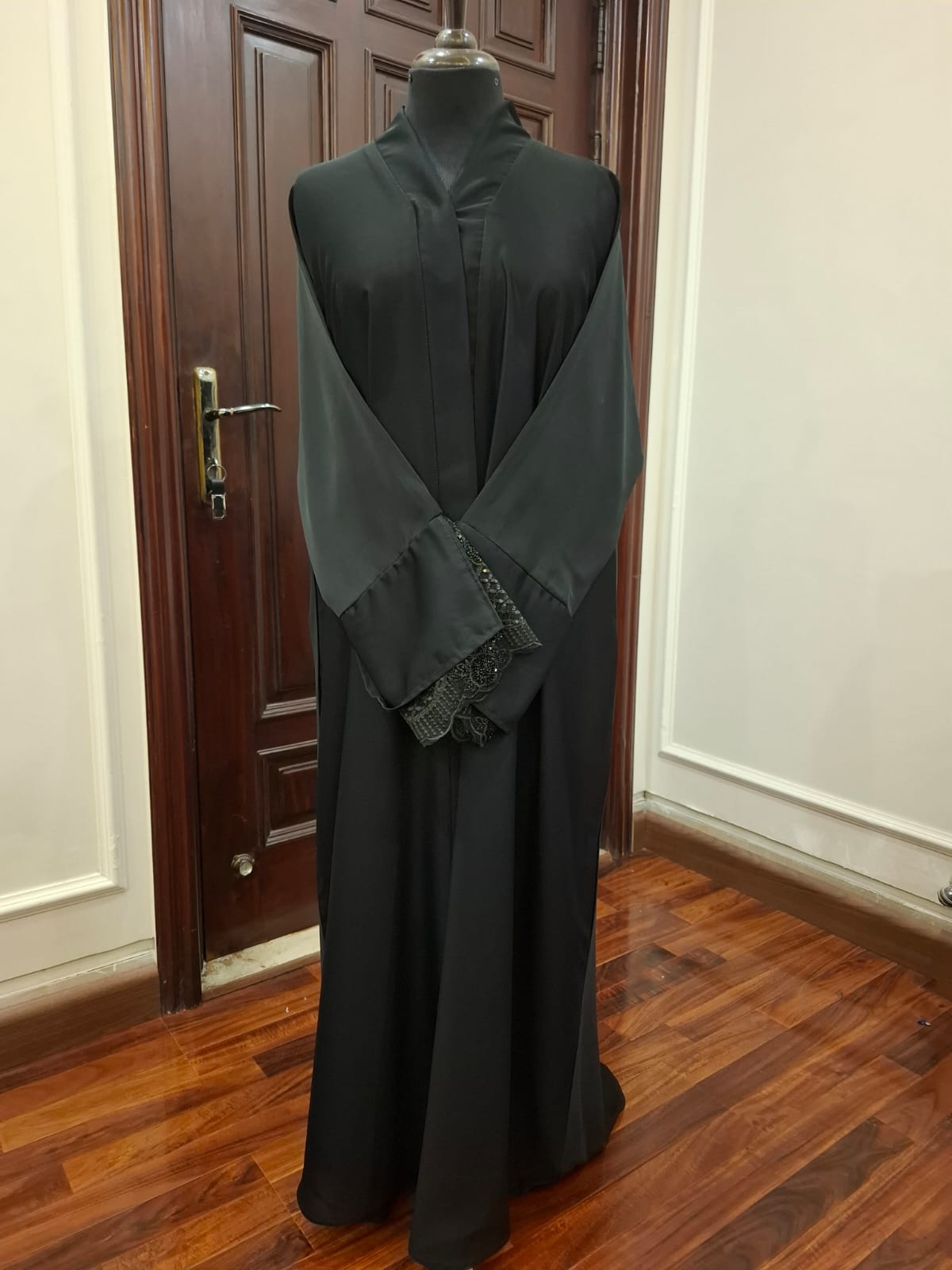Black dress on a mannequin in front of a wooden door.