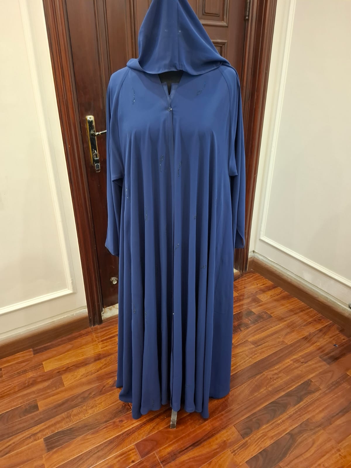 Blue hooded dress on a wooden floor with a door in the background