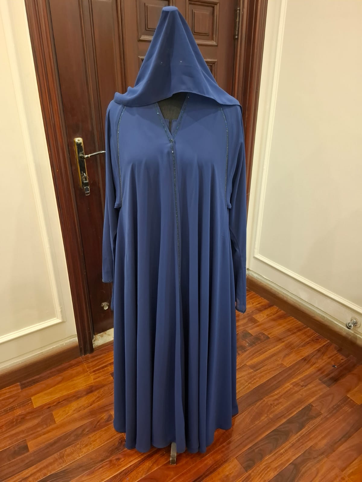 Blue hooded garment on a wooden floor with a door in the background