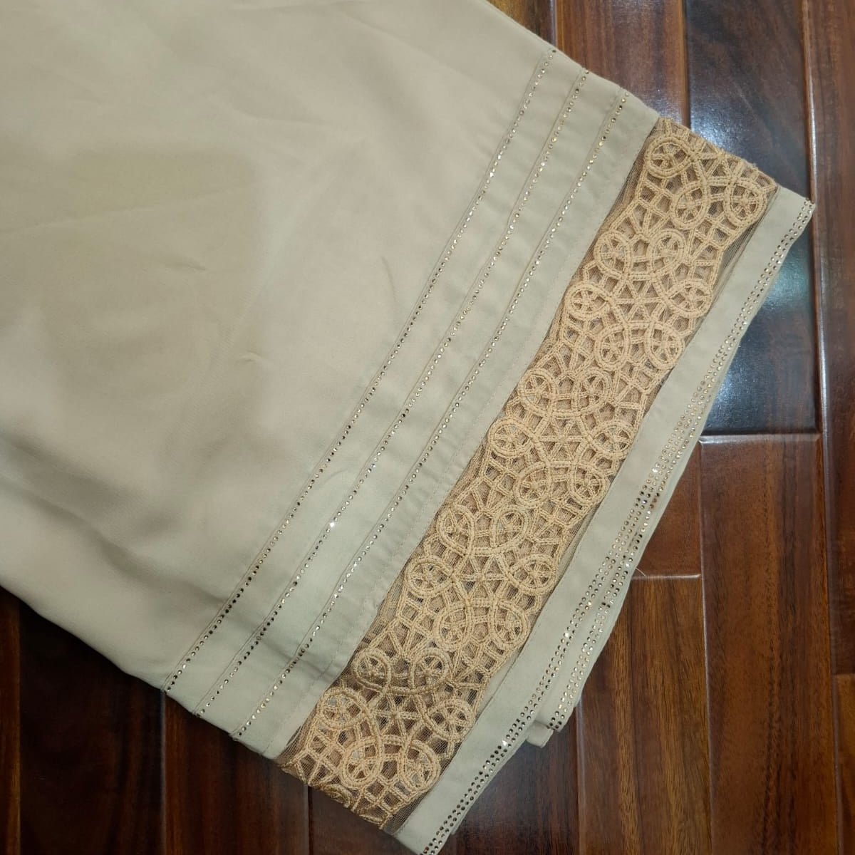 Beige fabric with lace trim on a wooden floor