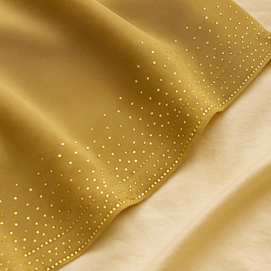 Gold fabric with small embellishments on a beige background